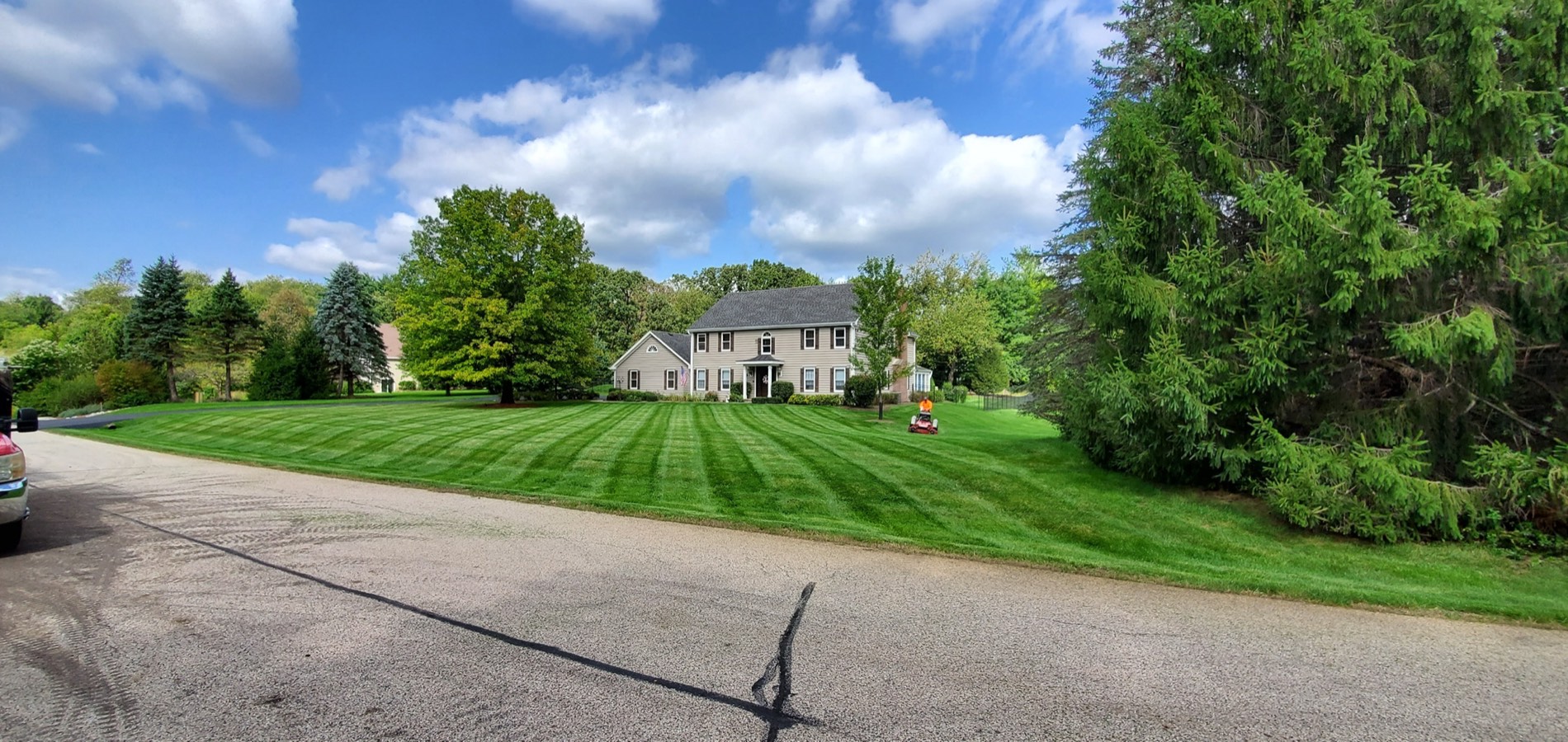 A professionally mowed residential lawn in McHenry County with a large home in the background