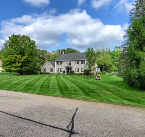 A professionally mowed residential lawn in McHenry County with a large home in the background