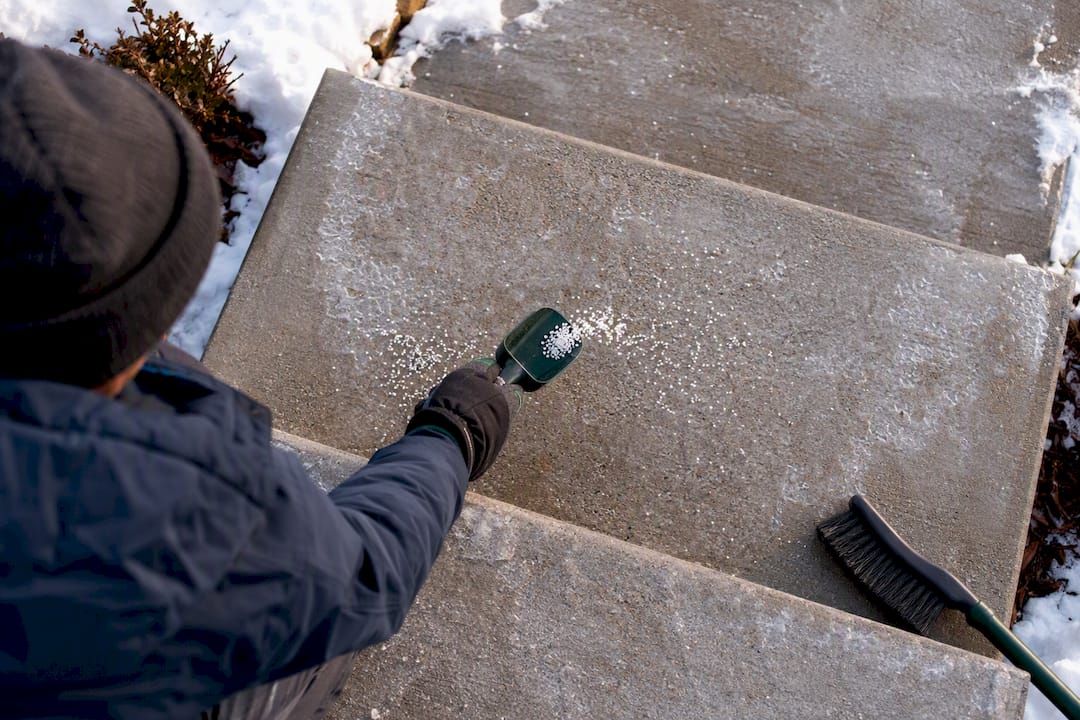 Homeowner applying ice melt to concrete